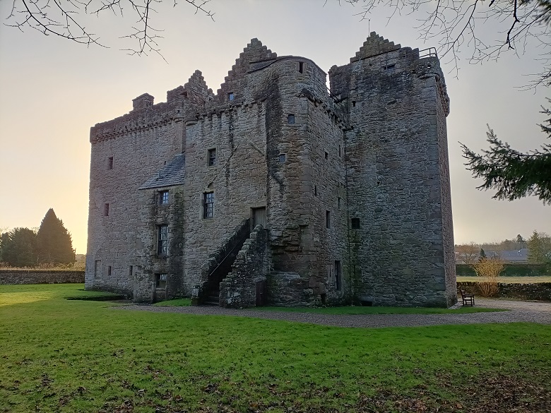 The exterior of a castle with many turrets and battlements. It can be imagined how the building was once two separate tower houses side by side. 