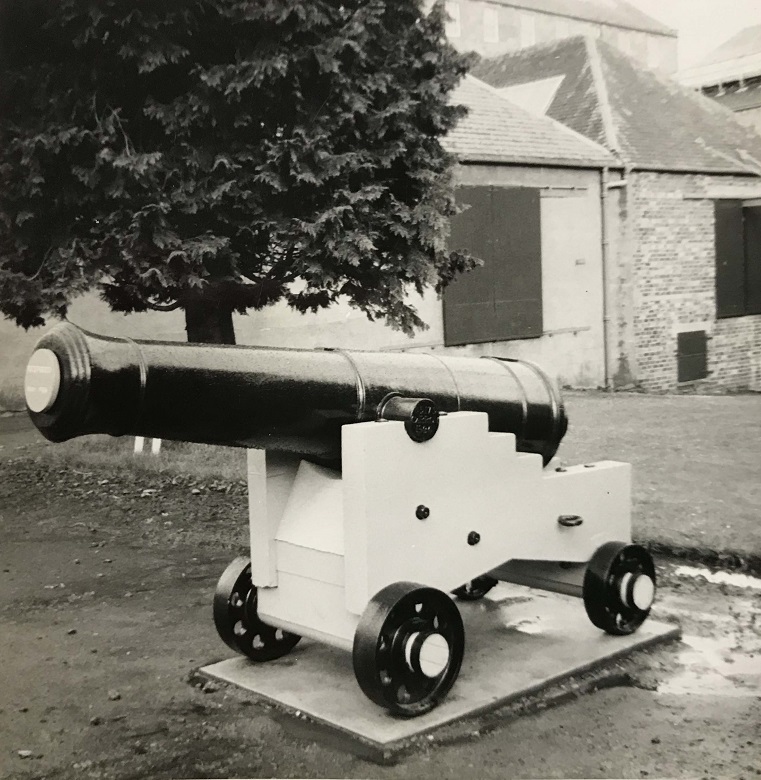 A black and white photo of a small cannon on a wooden frame with wheels