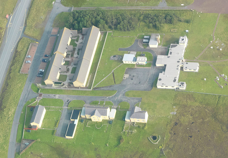 Aerial view of a complex of buildings in a rural landscape.