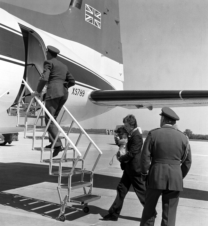 An archive photo of a corgi being carried onto a small plane