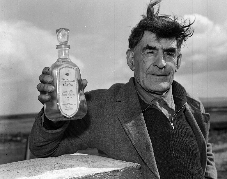 Archive photo of a man with windswept hair holding an empty bottle of whisky