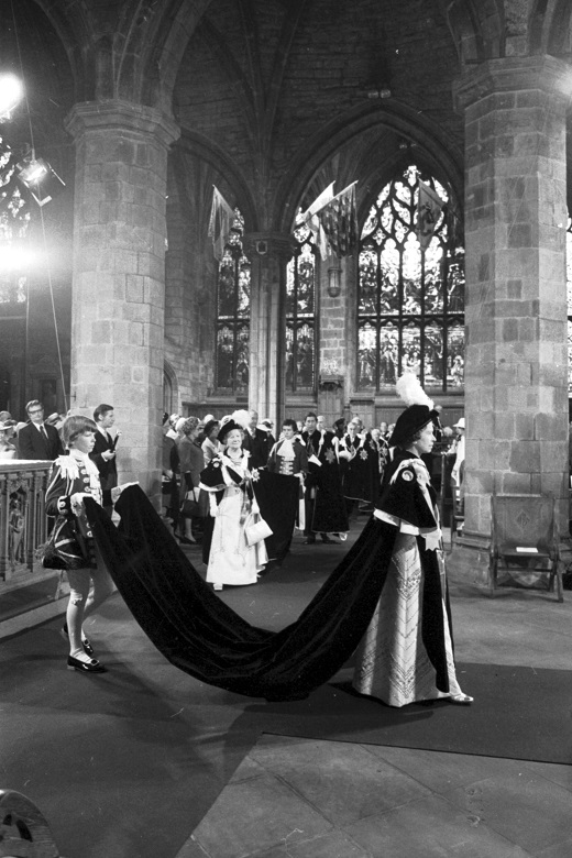 A black and white archive picture of the Queen dressed in ceremonial robes during a service in a cathedral. 