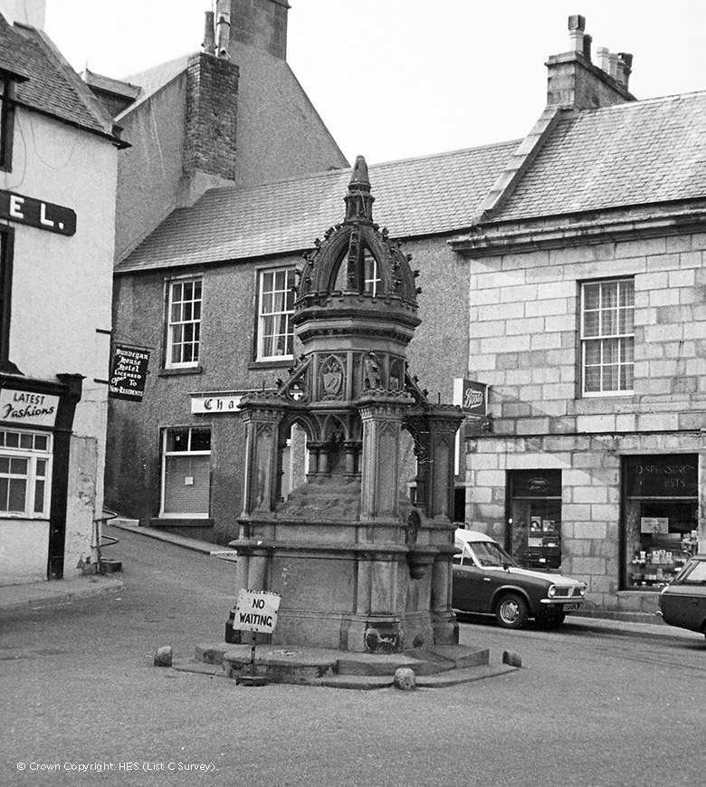 an orbately carved stone fountain in a small historic square