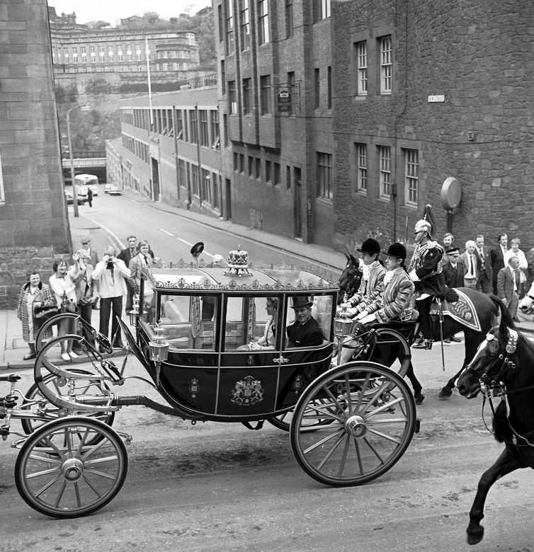 An archive photo of an ornate horse-drawn carriage conveying the Queen along Edinburgh's Royal Mile