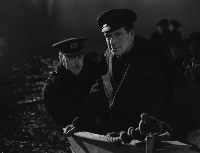 A still from a black and white film showing two men in a rowing boat