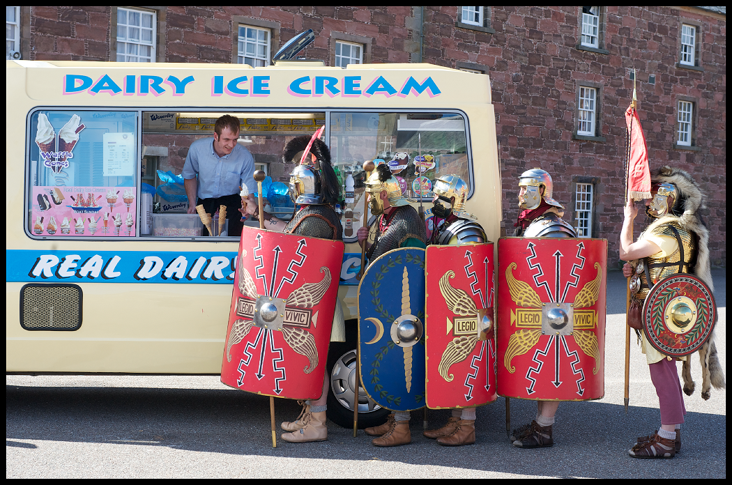 A group of people dressed in re-enactment clothes as Roman soldiers queuing at an ice cream van