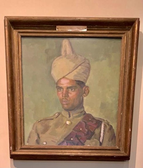 A portrait of an Indian soldier in a brown wooden frame.
