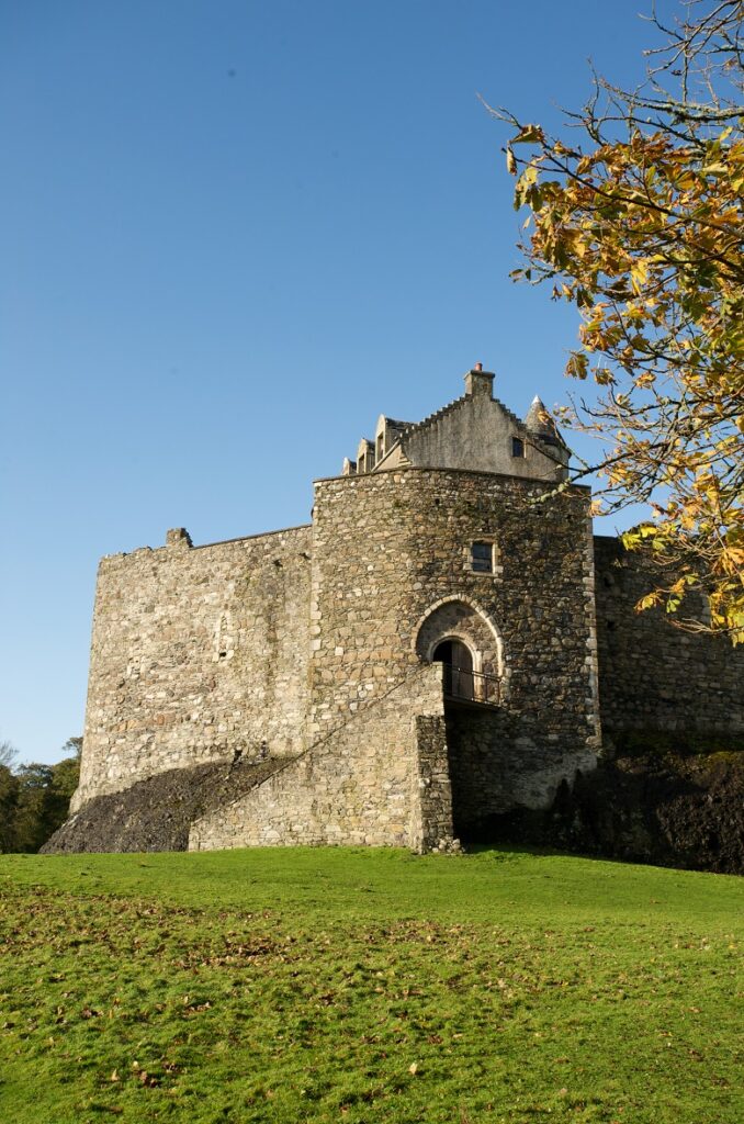 Exterior of Dunstaffnage Castle framed by autumnal trees.