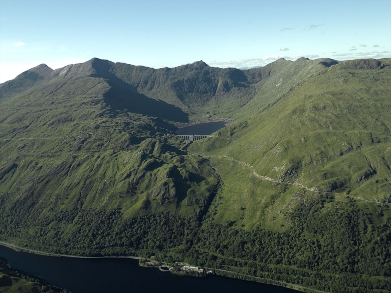 A dam and a reservoir built into the mountainside above a loch