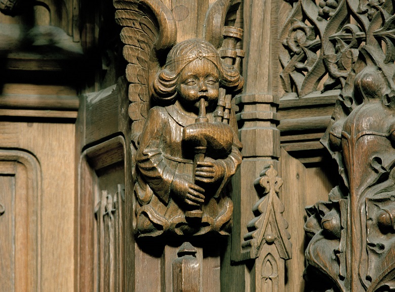 Detail of carved wooden angel playing bag-pipes.