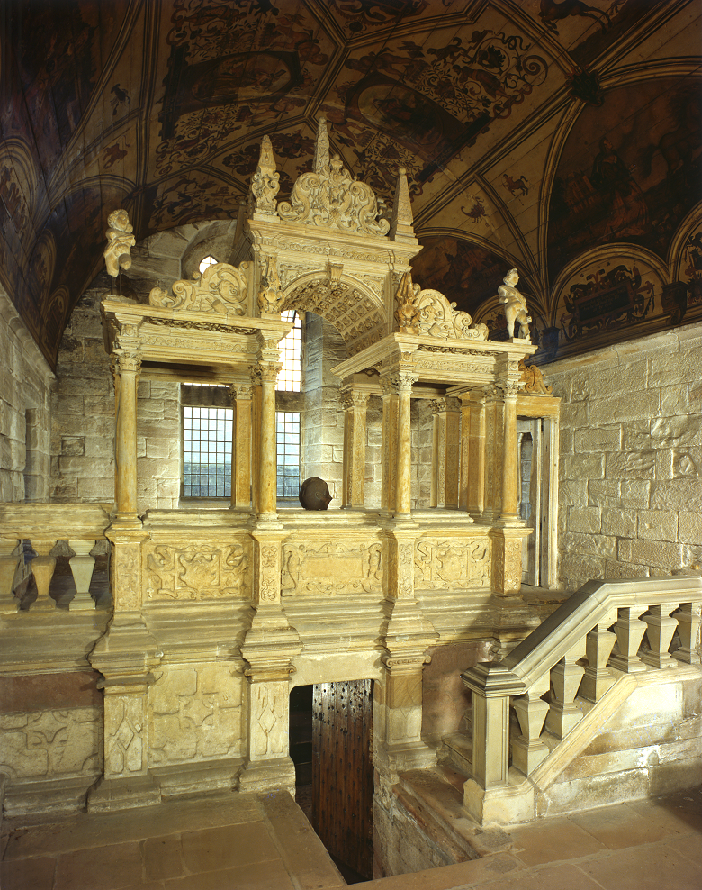 A richly carved tomb monument with delicate balustrades and pillars topped by cherubs. There is a heavy studded door in the centre leading to a burial vault.
