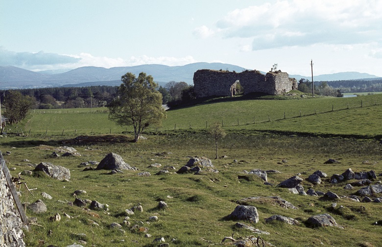 A rocky field in front of the ruins of Castle Roy with mountains in the background