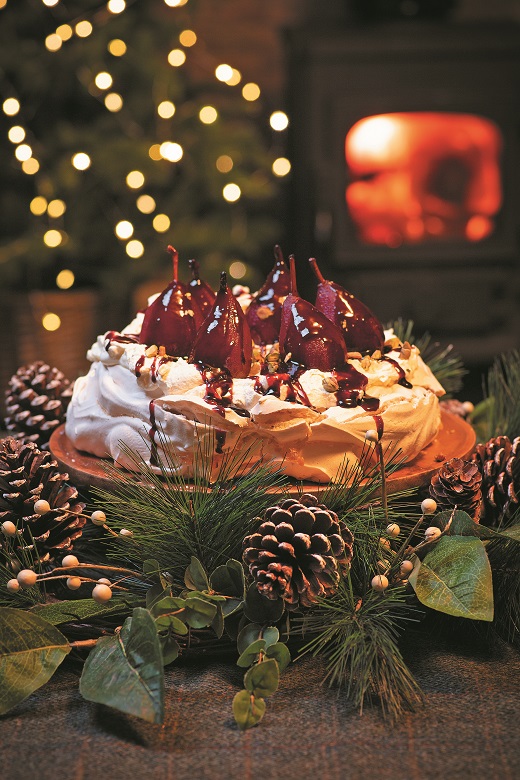 A pavlova ready to eat and a table decorated with a Christmas wreath