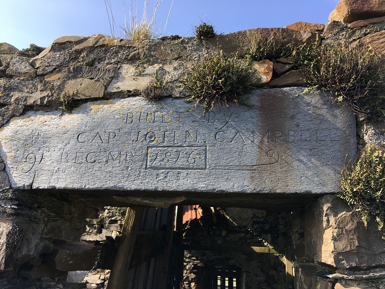 The lintel above the door of an abandoned house enscribed with the name of the man who built it, a John Campbell in 1876
