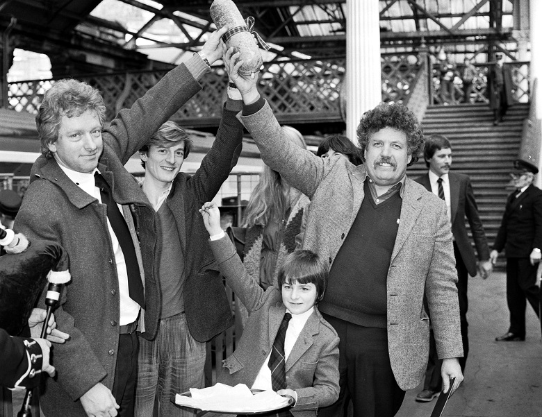 A young boy points to a haggis being held aloft by three men during a photocall at a train station
