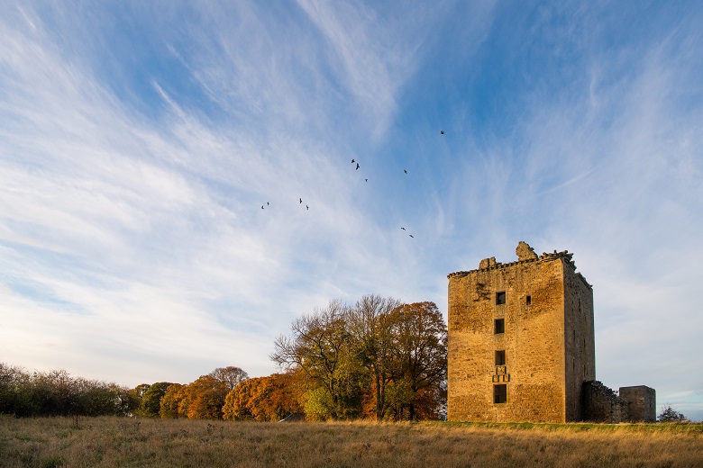 Ruined towerhouse of Spynie Palace on a clear day with wispy clouds above.