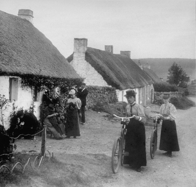 An archive photo of women gathered outside one of a row of thatched miner