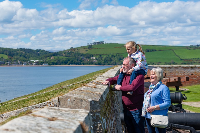 Grandparents and a grandchild look out to sea from the ramparts of Fort Geroge