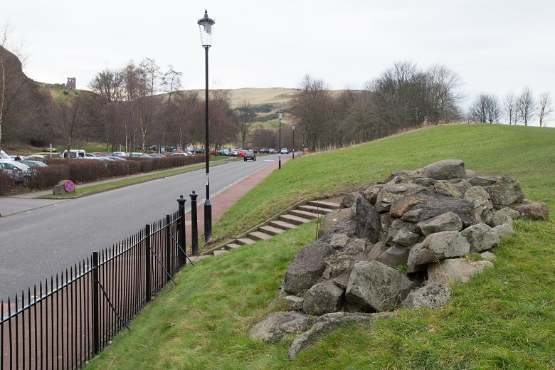 A small stone cairn beside a road entering a park