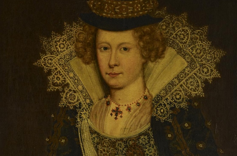 A richly dressed woman wears her hair in buns on either side of her head. She has an enormous lace ruff and wears jewellery and richly embroidered clothing.