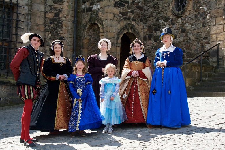 Two little girls in princess dresses pose with adults re-enactors in costume.