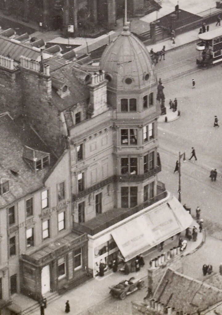 View of the west end corner of Princes Street from an elevated angle. Showing the building as Robert Maule department store with lettering on the side of the building and large white awnings.