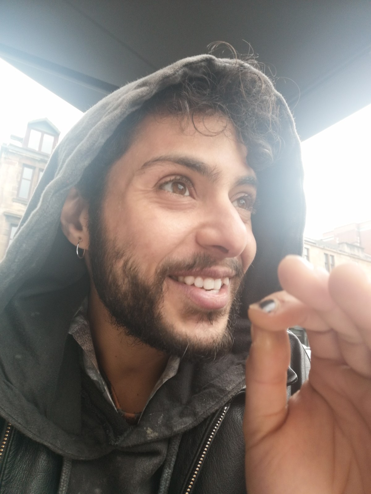 a close up photo of a person wearing a hoodie smiling at someone off-camera