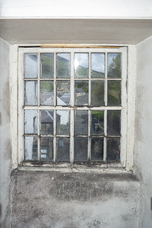 A historic wooden window with small panes in four rows of six