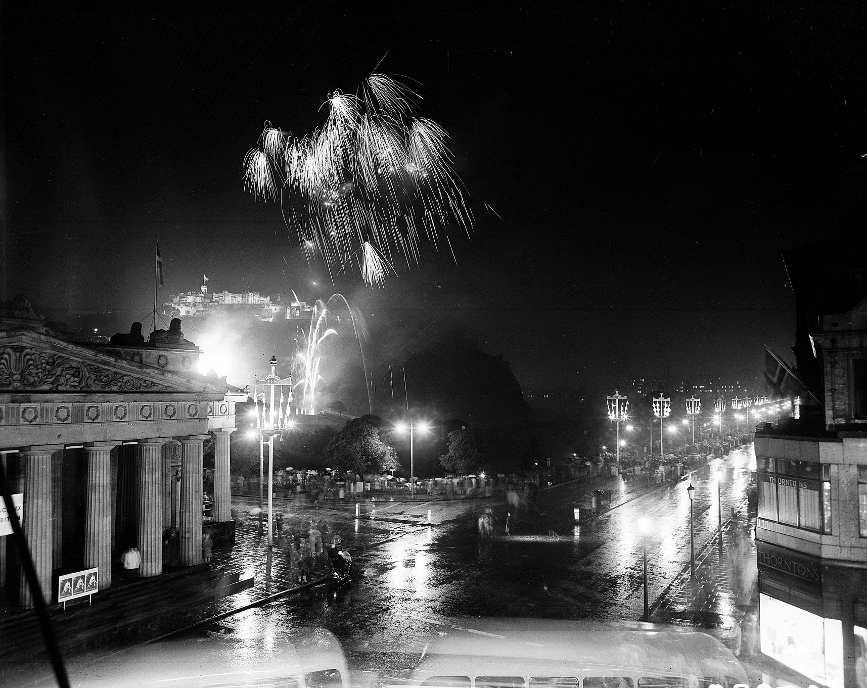 A black and white archive photo of the Edinburgh night sky lit up by fireworks over Edinburgh Castle and Princes Street. 