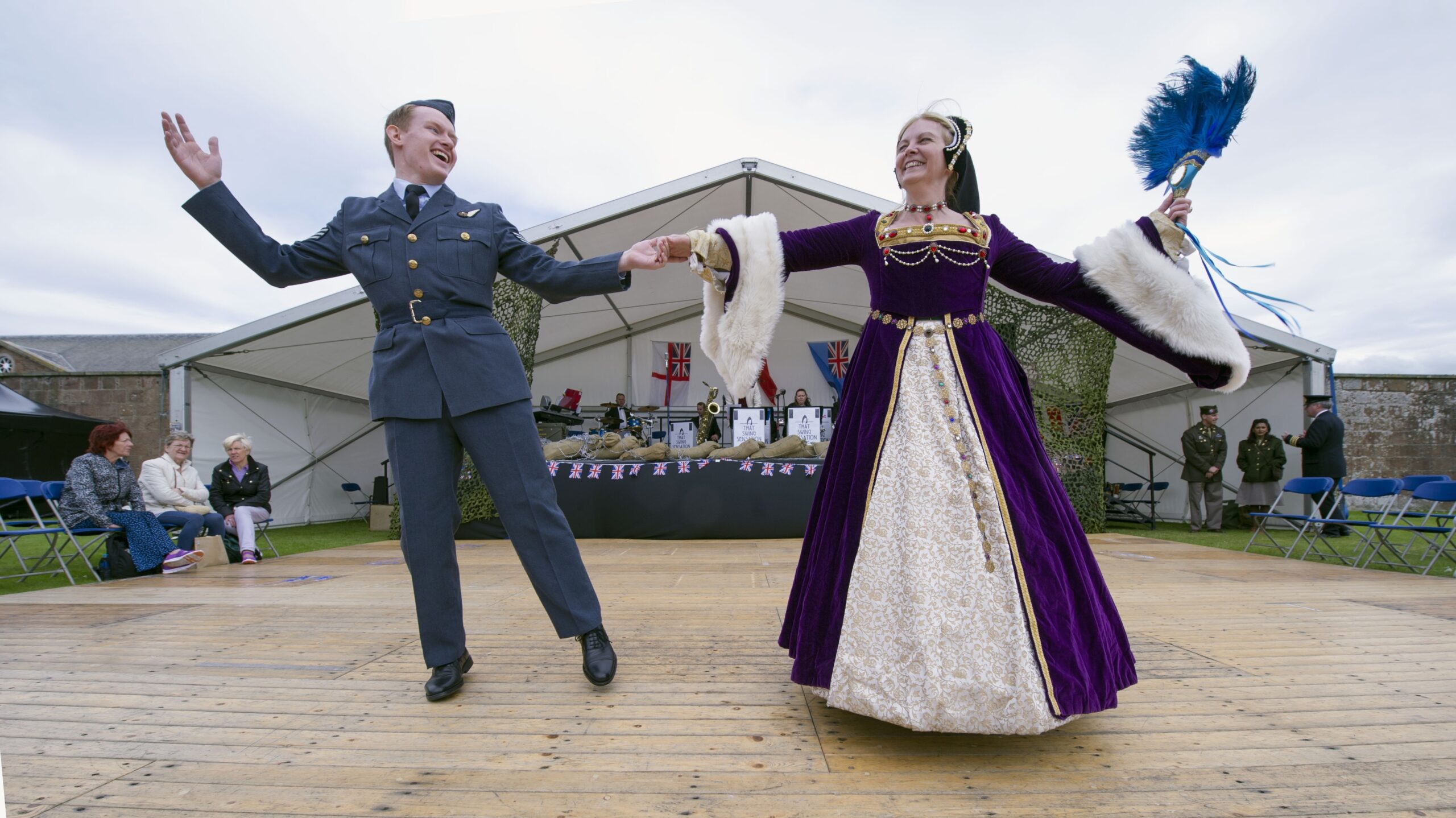 A women dressed in a purple, medieval dress dancing with a man dressed as a WWII solider at Celebration of the Centuries