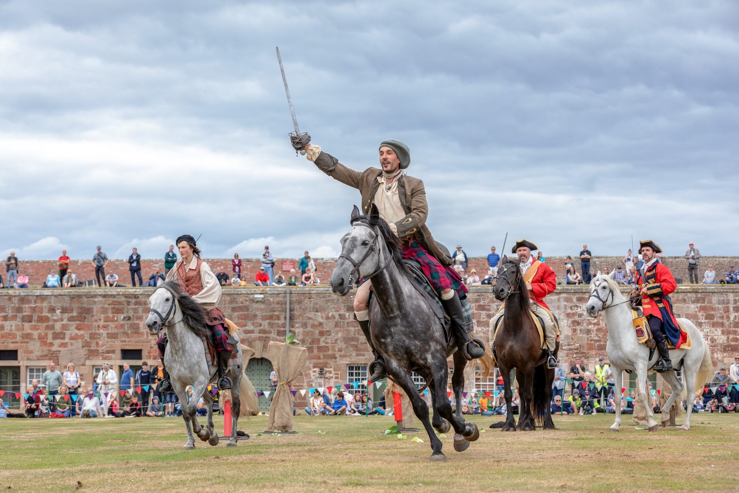 Four reenactors dressed as soldiers riding on horses at the King and Clansmen event at Fort George. 