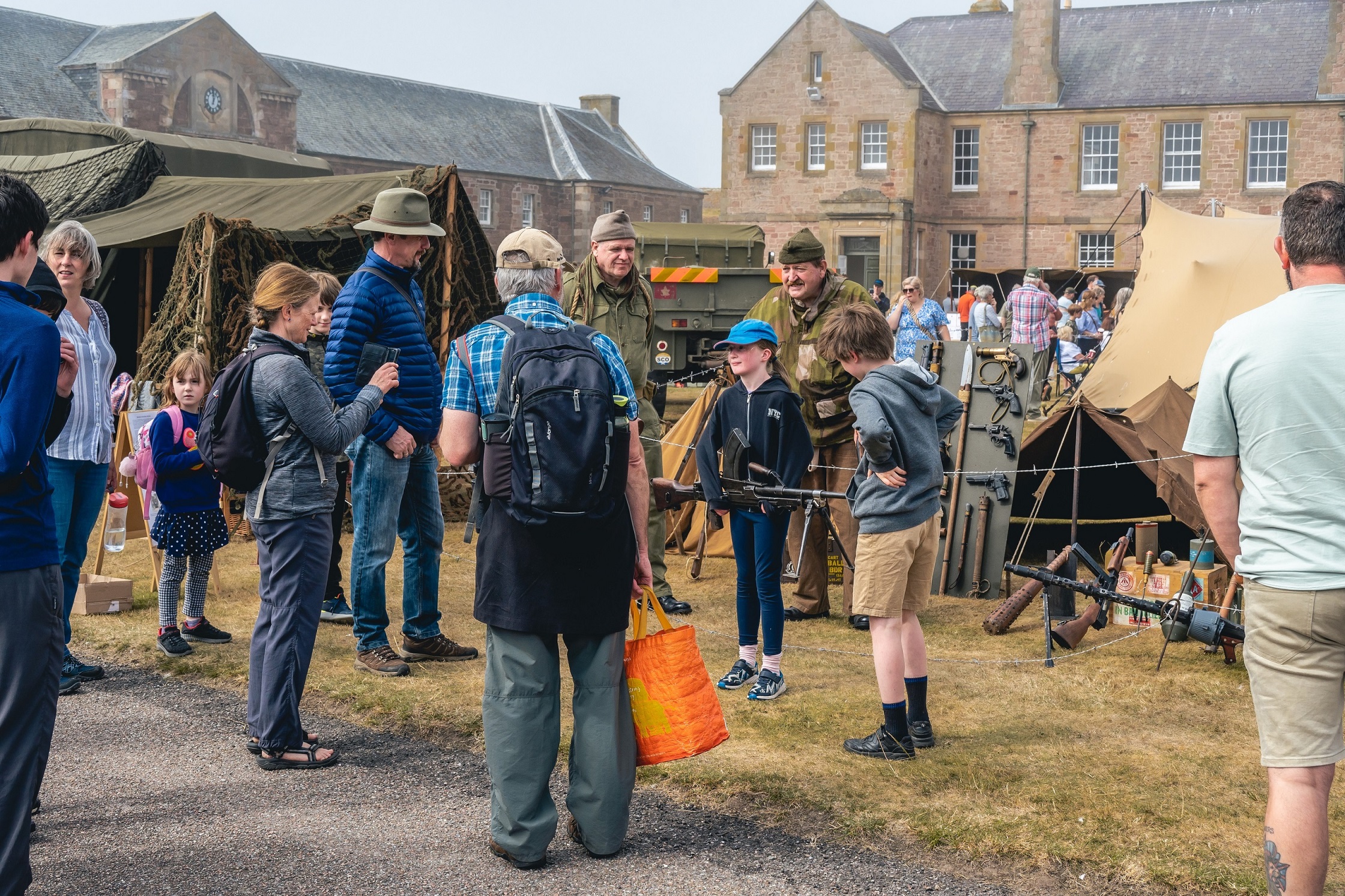 A group of people gathering in front of tents at the Celebration of the Centuries event at Fort George.