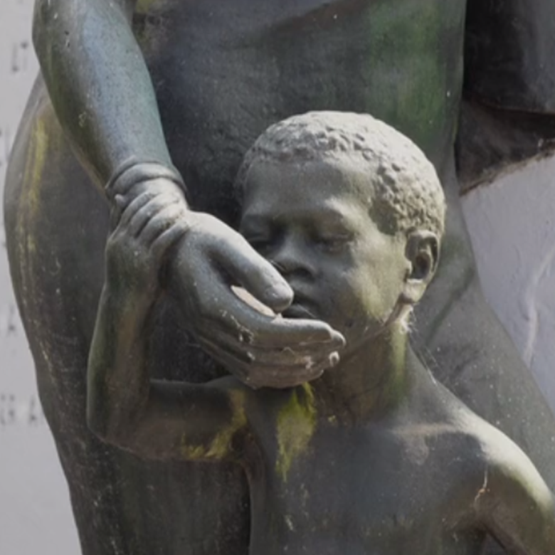 A bronze statue of a young Black child. Their face is being cradled by their mother.