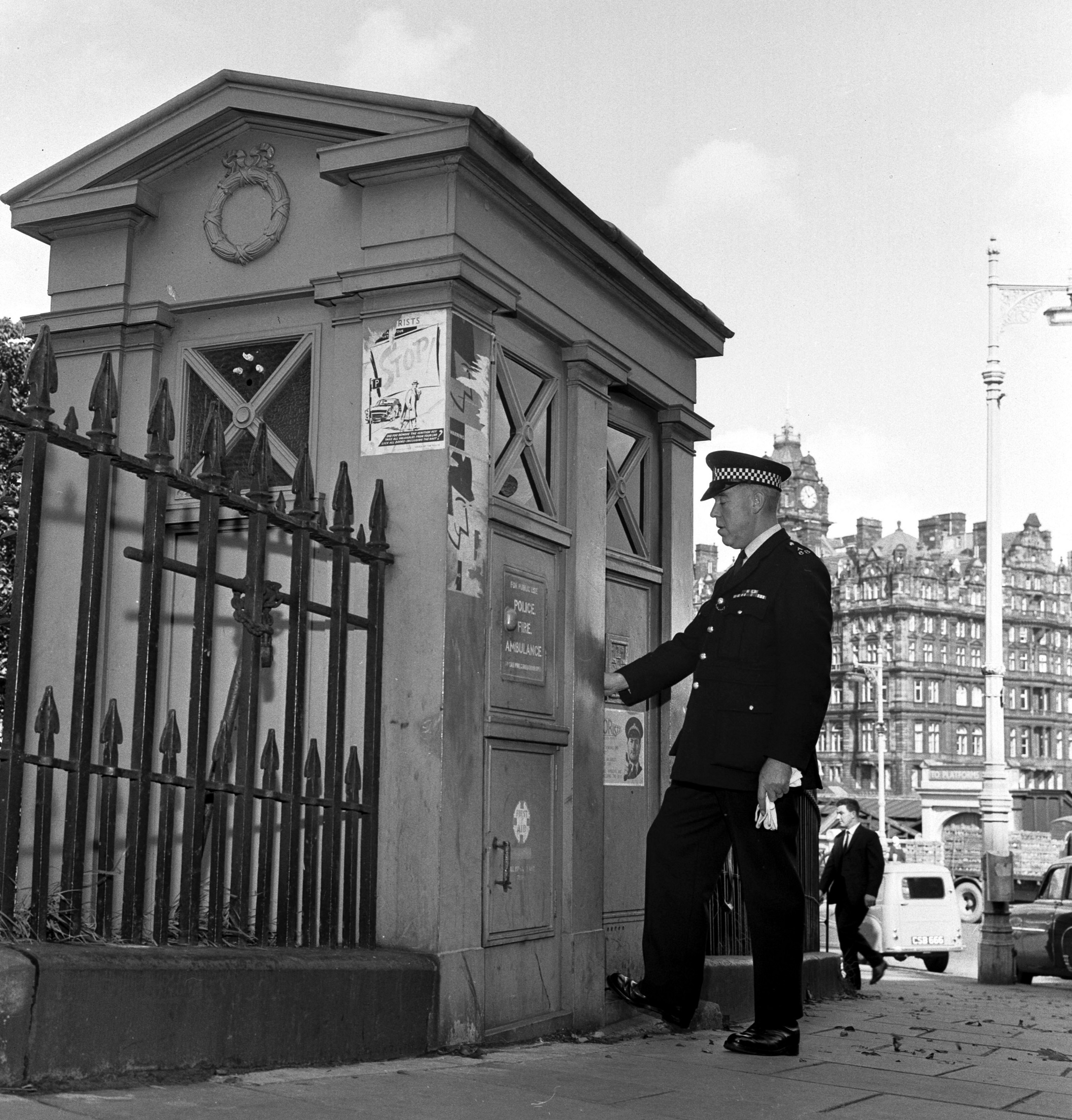 A black and white archive photo showing an Edinburgh police man entering or exiting a police box. 