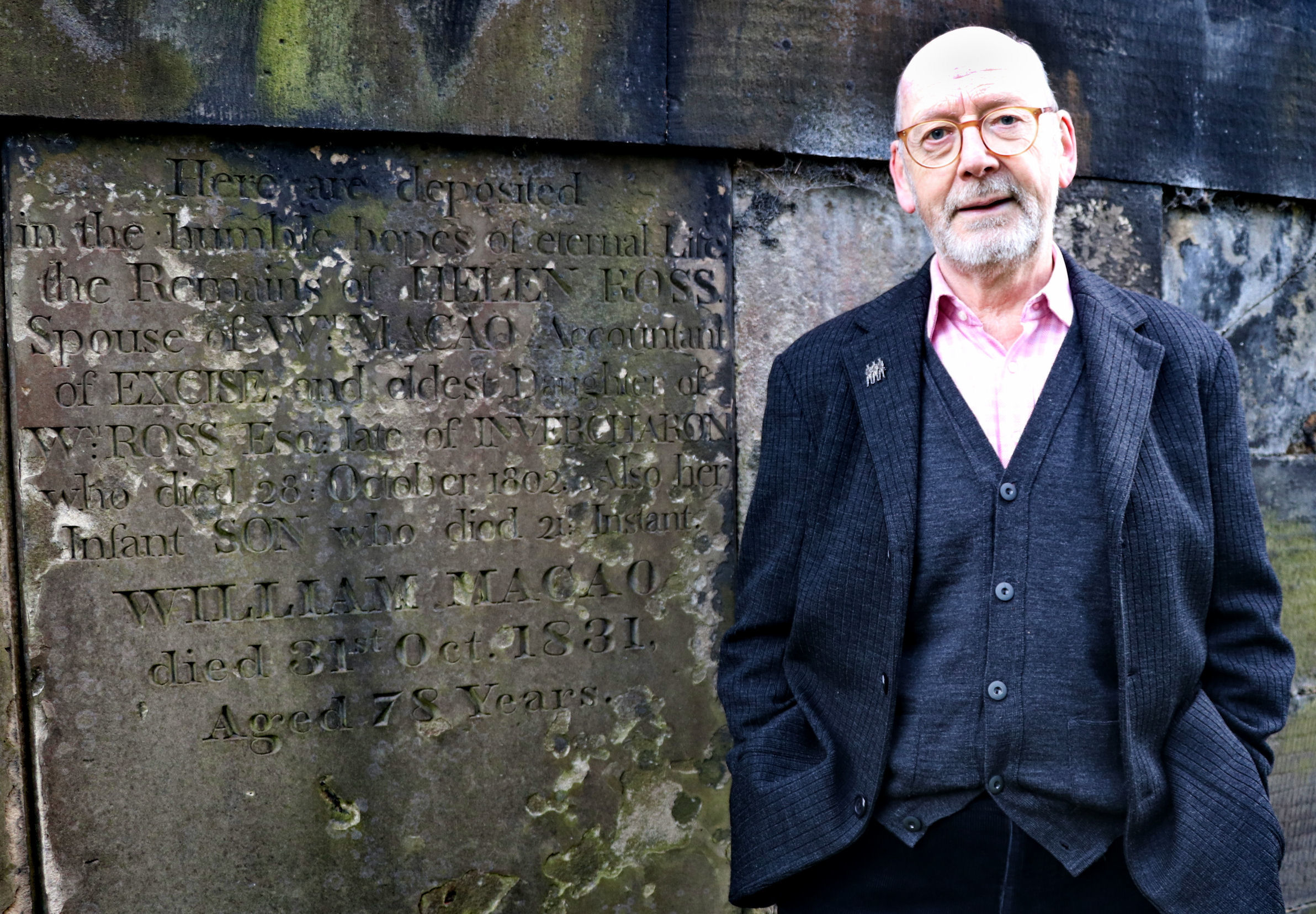 Barclay Price standing next to the gravestone of William Macao