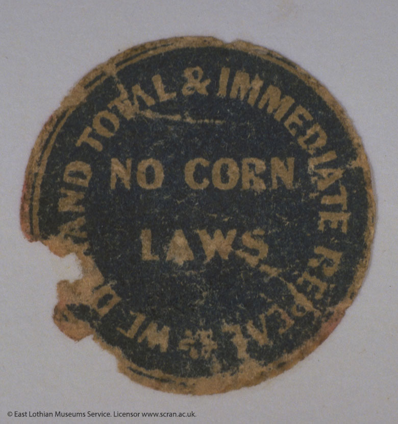 A round sticker. The middle says "No corn laws". Around the outside it reads: "WE DEMAND TOTAL AND IMMEDIATE REPEAL"