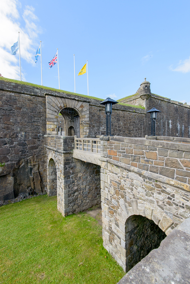 the Outer Defences at Stirling Castle. Three flags fly above the entrance archway.