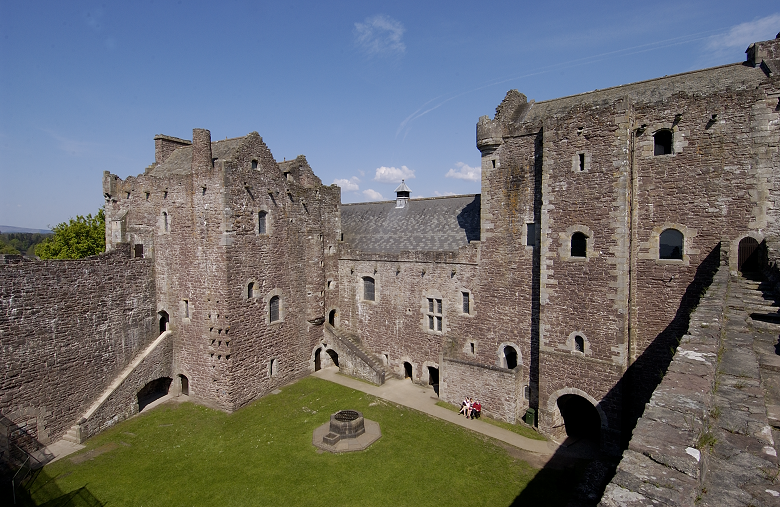 The courtyard of Doune Castle flanked by high walls and towers. 