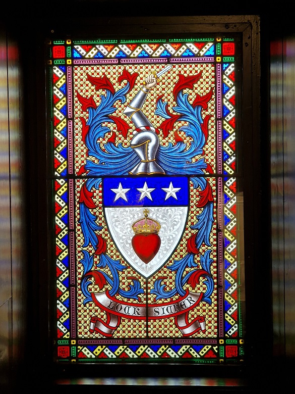 An intricate stained glass window featuring the arms of the Earl of Douglas, with a prominent red heart at its centre. 