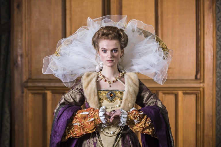 A woman wearing a Renaissance reenactment dress and a very high tull collar