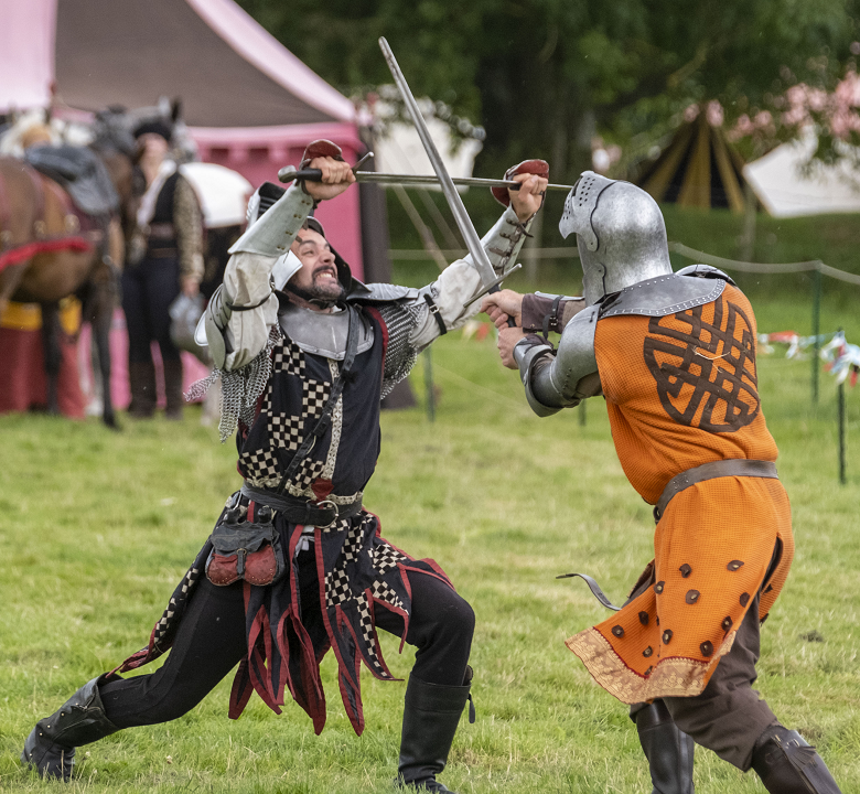 Two historical reenactors engaged in a mock sword fight. 