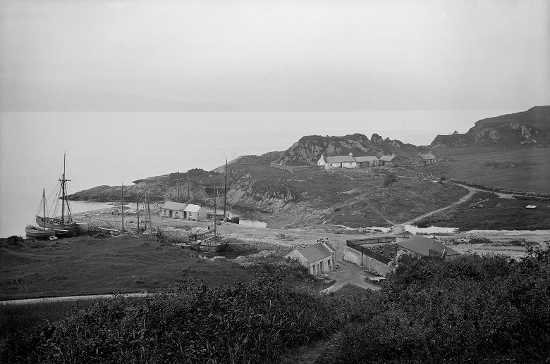 A black and white archive photo of An Sailean lime works showing several modest buildings and boats arriving at a small harbour 