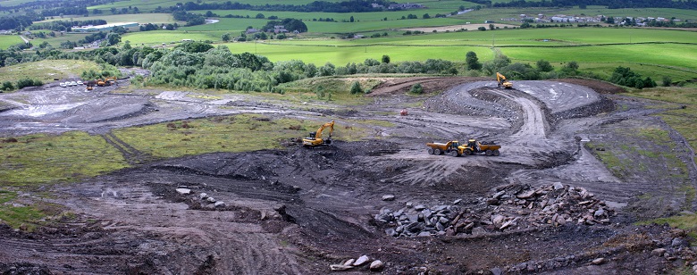 A photo of diggers at work constructing Crawick Multiverse on the site of a former open cast mine. At this stage, the site is muddy and ugly.