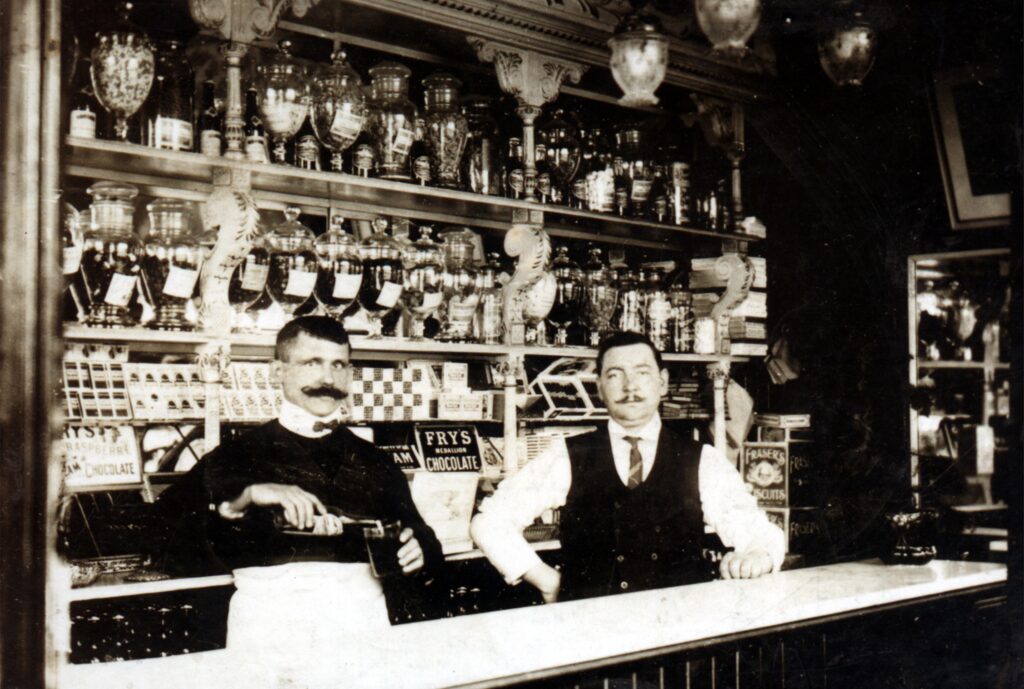 Black and white archive photo showing two men behind a counter.