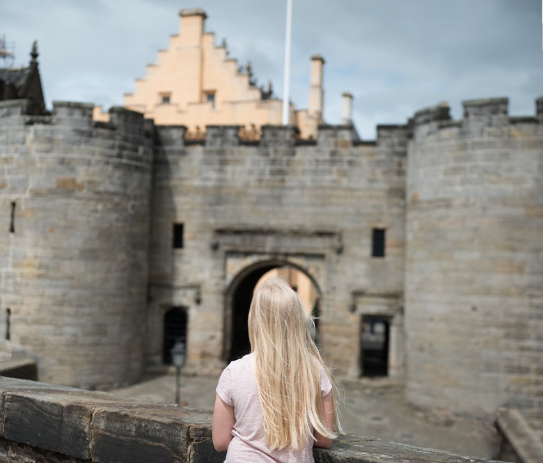 A young girl standing on a battlement at Stirling Castle, in the modern day.