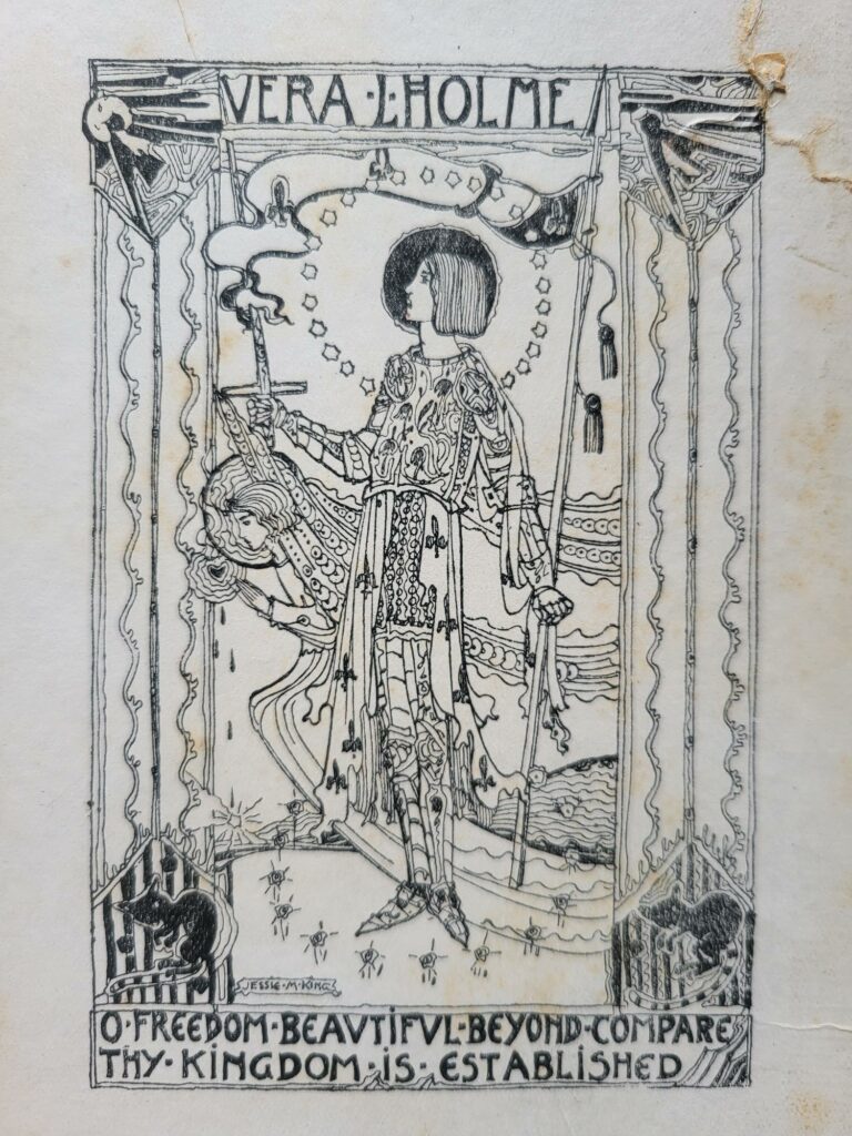 A black and white illustration in the arts and crafts style. The figure of Joan of Arc stands in the middle of the image holding a sword and accompanied by an angel. Text at the top reads Vera L Holme. Text at the bottom reads: O freedom beautiful beyond compare thy kingdom is established.