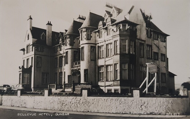 The grand façade of the Belle-Vue hotel with cars parked in front of the entrance.