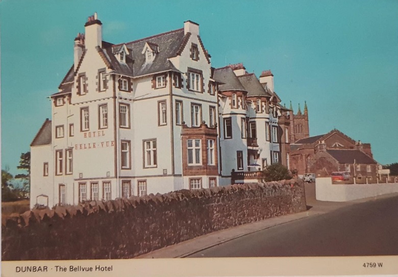 A colour postcard showing a large white hotel built with towers, bay windows and ornamental features 