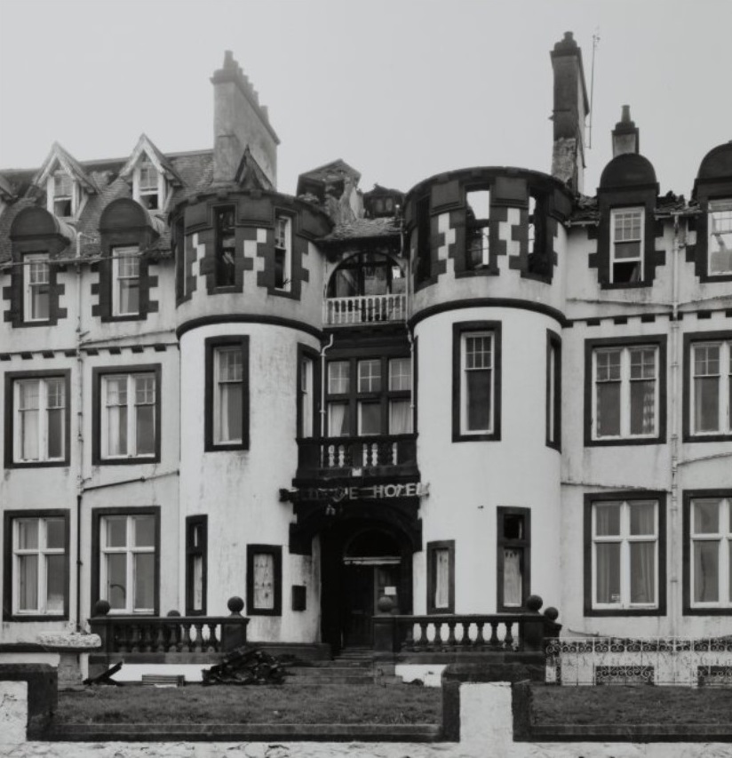 An archive photo showing the front of the Belle-Vue hotel. There is clear fire damage to the top floors with the roof having burnt away above the main entrance. 