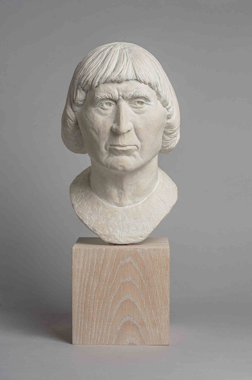 A reconstruction of Robert the Bruce's head on a wooden plinth. He is depicted with a surly expression, with clear skin and a distinctive page boy haircut.